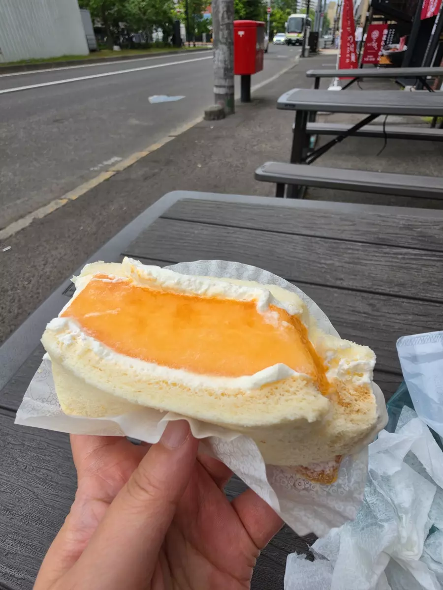The original phone snapshot: a cream-filled pastry held up on a street bench